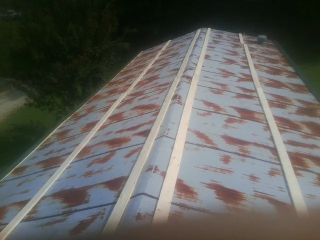 Rusted metal roof panels with new wood purlins before replacement — Storm Damage Roof Repair in Locust Gap by Roofing Brothers