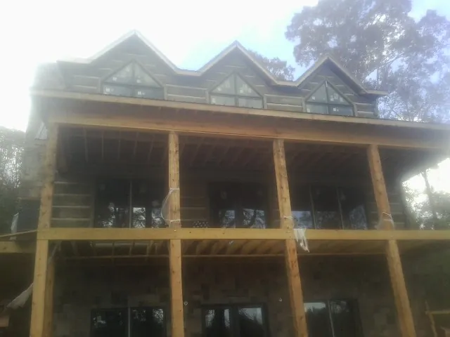 Dormers and porch framing on a large log home under construction — Roof Coating work by our crew in Locust Gap