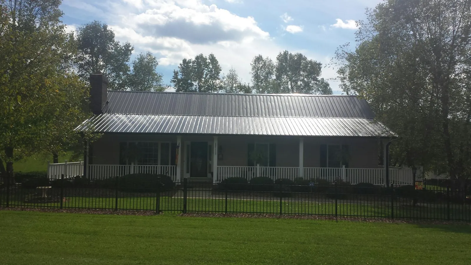 Gray metal roof on a brick ranch with a full width front porch — Gutter Guard Installation work by our crew in Locust Gap