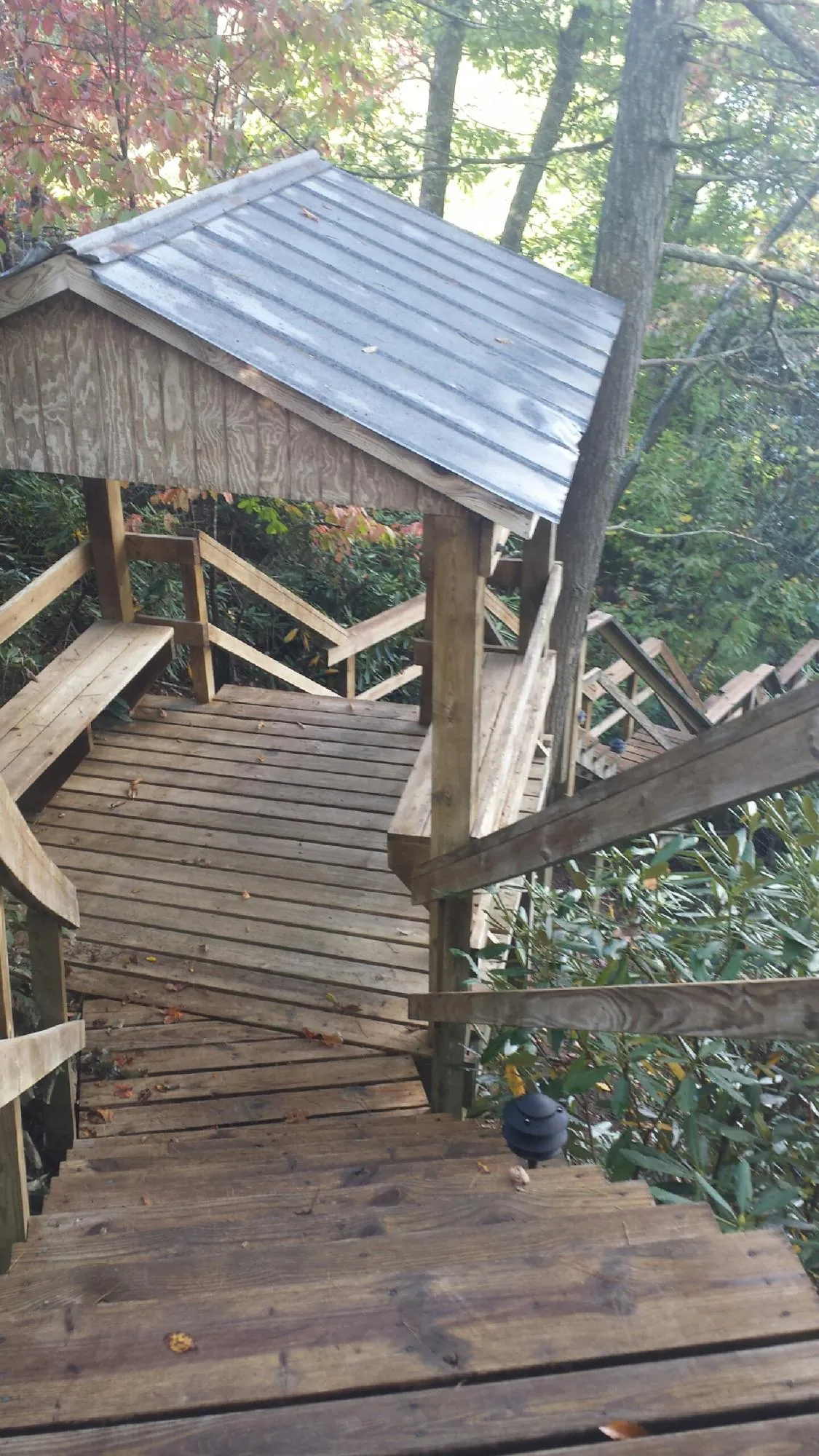 Metal roofed shelter over wooden steps on a wooded walkway — Skylight Repair & Installation work by our crew in Locust Gap